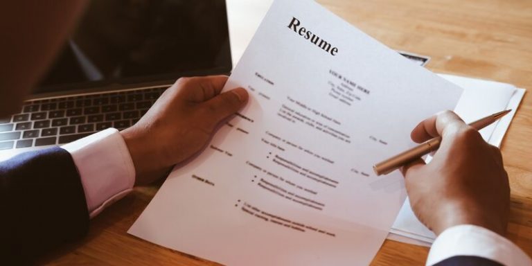 Pessoa analisando currículo em mesa de madeira