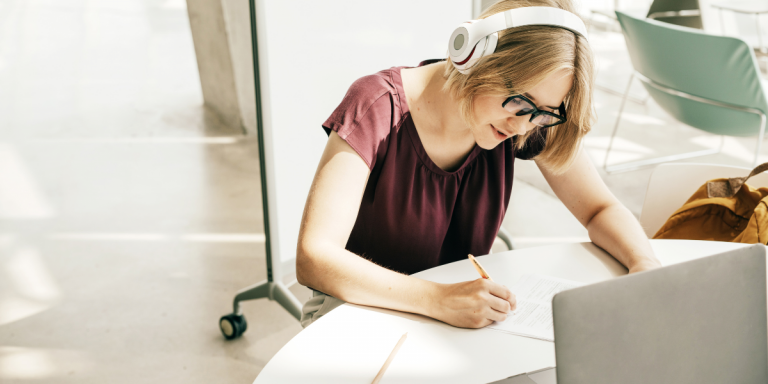 Mulher com fones escrevendo em um caderno