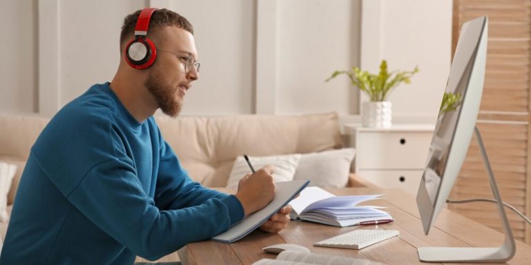 Homem estudando com fones de ouvido e notebook.
