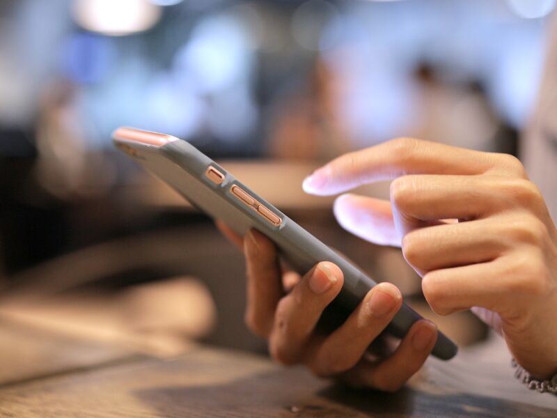 Pessoa utilizando smartphone em ambiente de café.