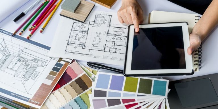 Mesa com materiais de design e um tablet mostrando plantas
