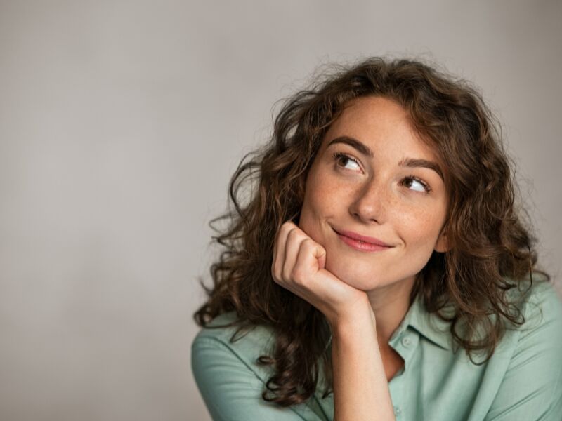 Mulher pensativa com cabelo Cacheado e sorriso