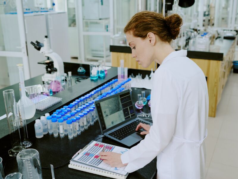 Cientista trabalhando em laboratório com laptop e equipamentos