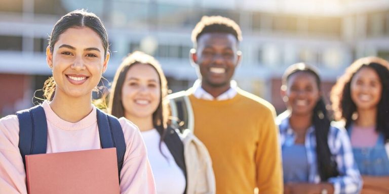 Grupo de estudantes sorrindo em frente à escola.
