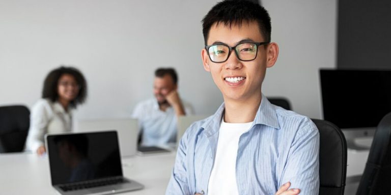 Jovem asiático sorrindo em escritório moderno.
