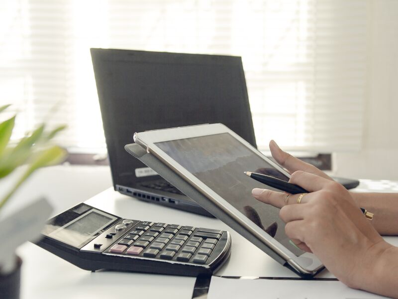 Pessoa usando tablet e calculadora em mesa de trabalho.